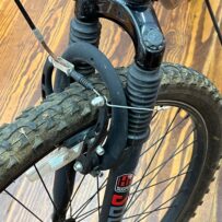 Front view of a Hyper Shocker 26 bike highlighting the suspension fork, handlebars, and knobby tires.